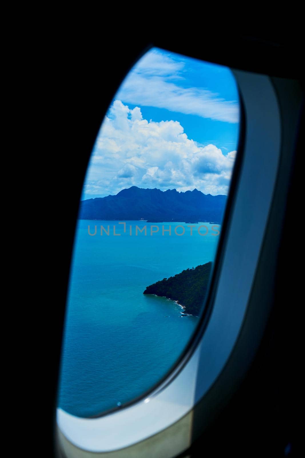 A view of a tropical island from the window of a landing plane