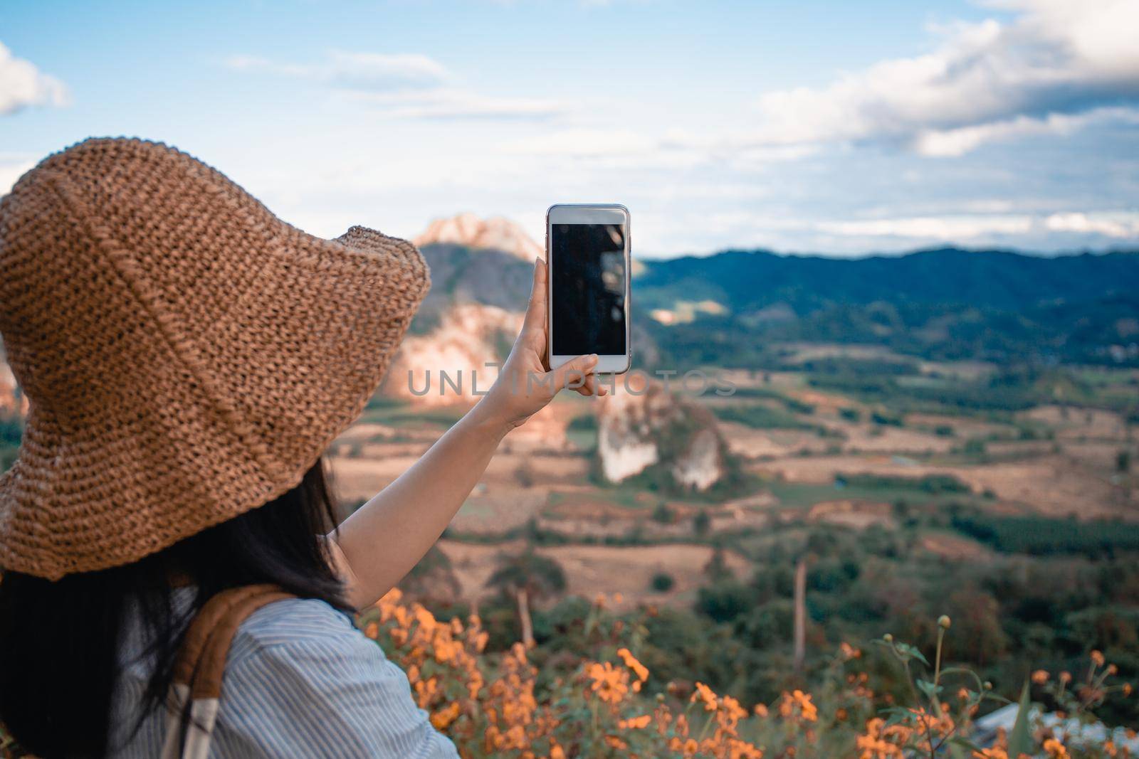 The girl take photo with smart phone on balcony bar at Phu Lang Ka mountain landmark in Phayao province Thailand