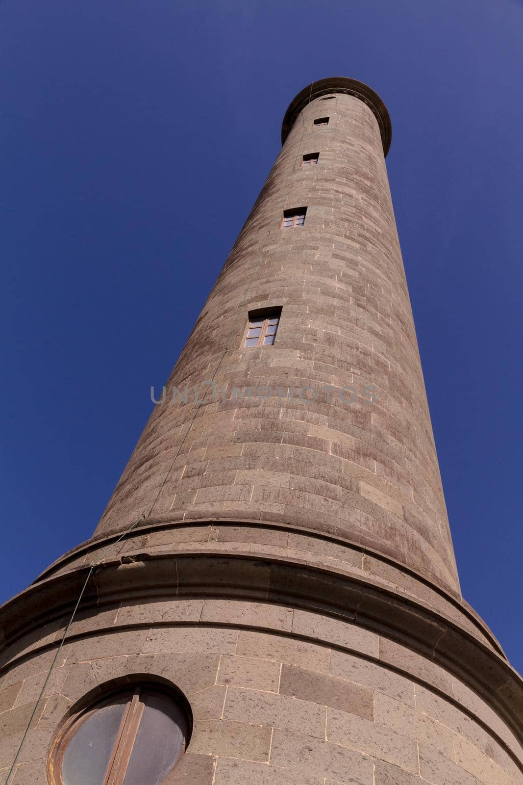 Low-angle view of Maspalomas' lighthouse against a clear blue sky on a sunny day