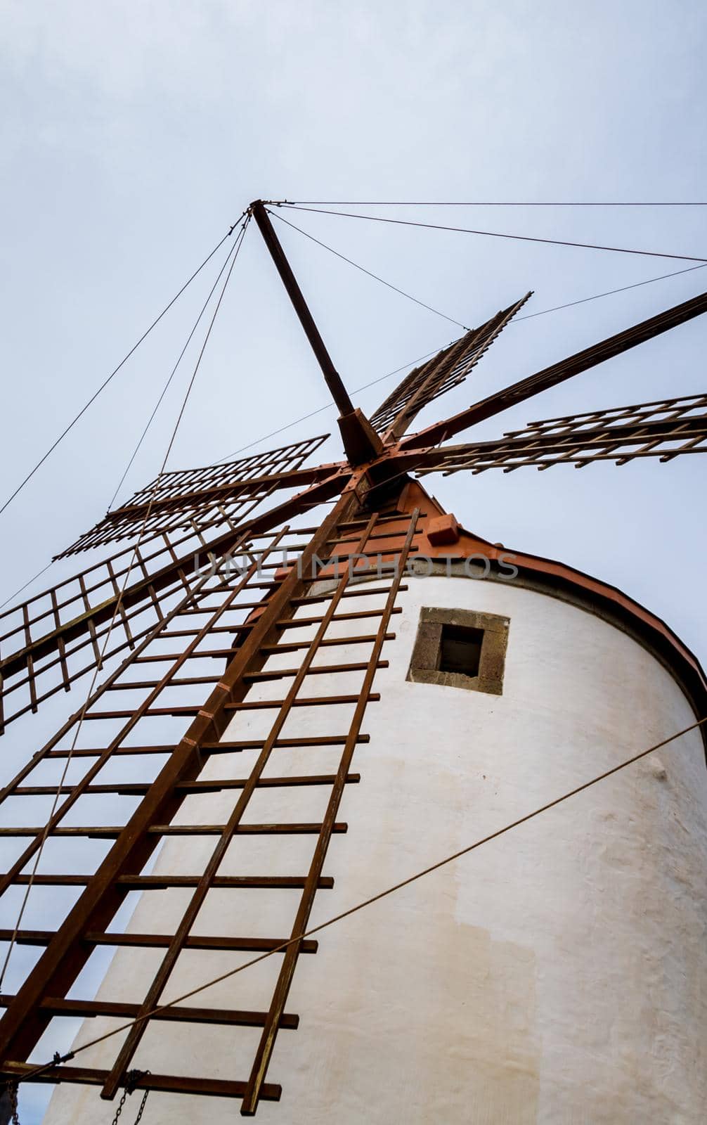 Low-angle view of an old white windmill with wood blades