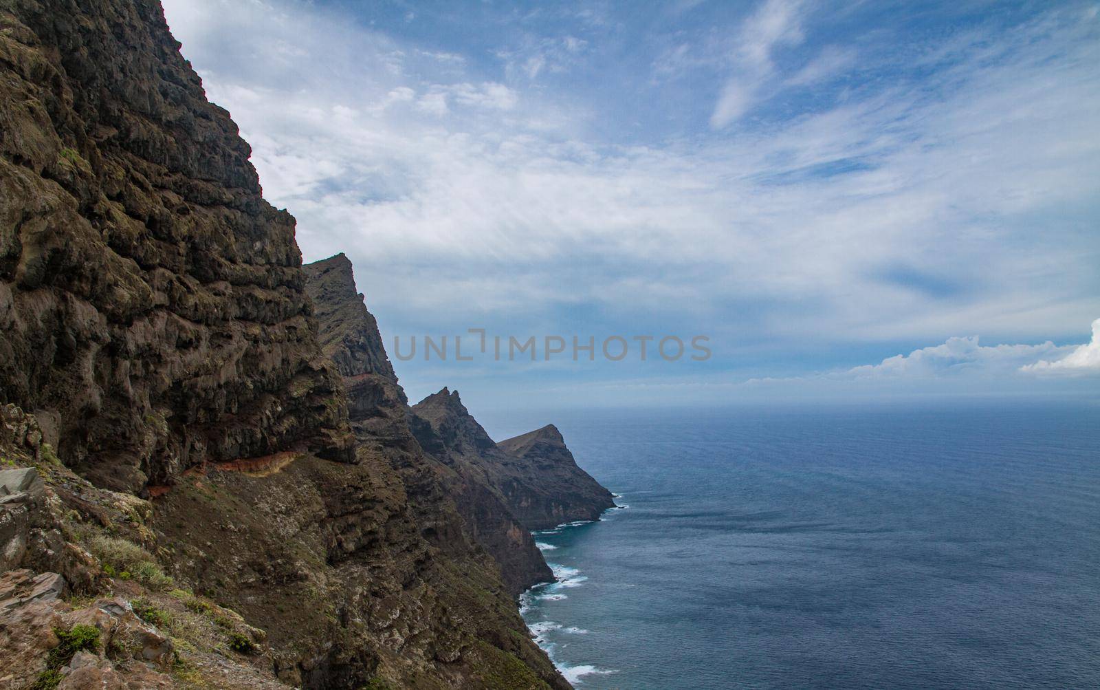 Scenic of a rocky cliff by teh sea on a sunny day