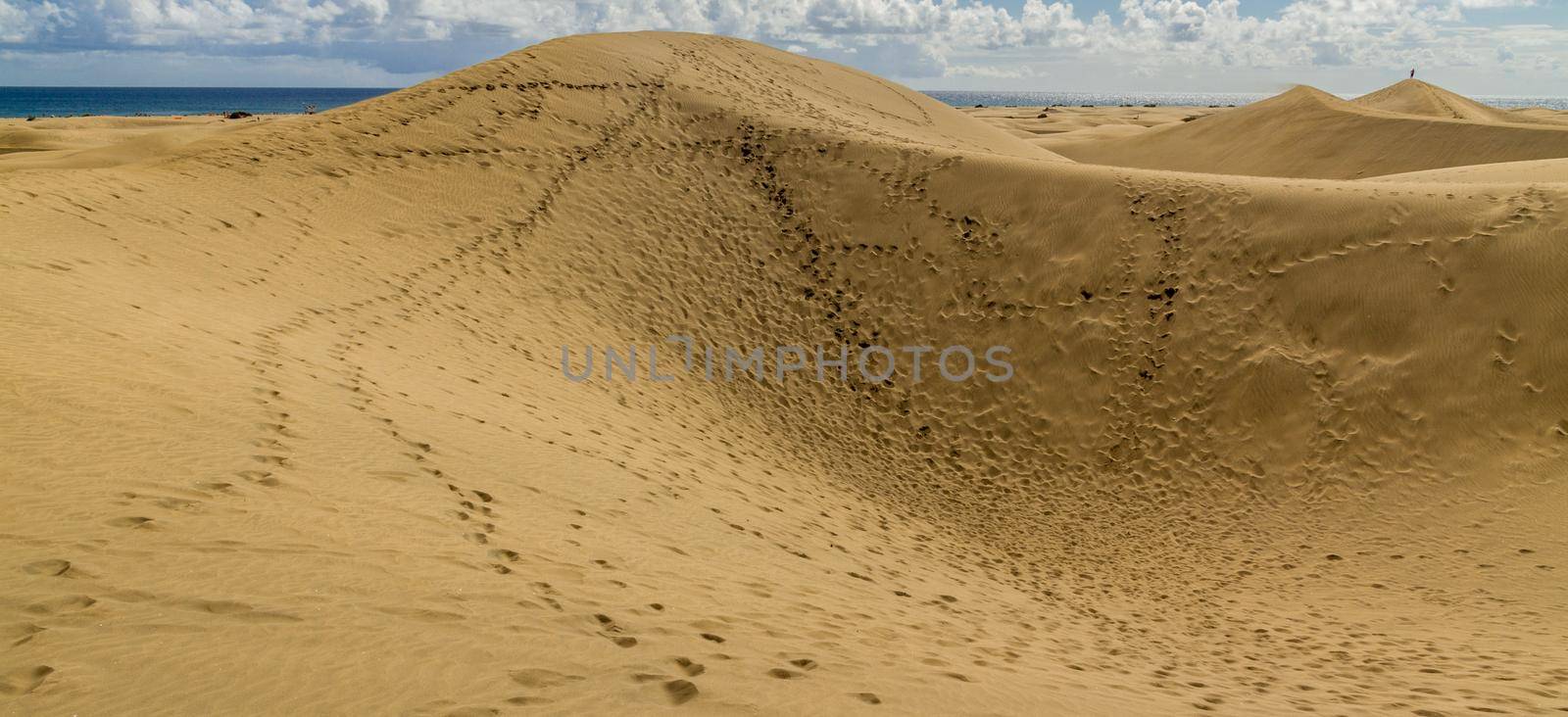 Wide-shot of sand dunes covered with footprints at teh beach on a  sunny day