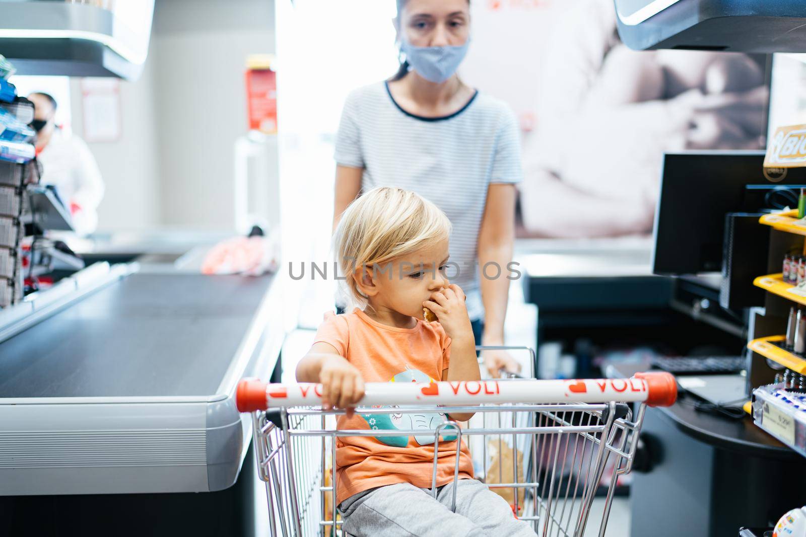 Mom and daughter in a supermarket trolley at the store checkout. High quality photo