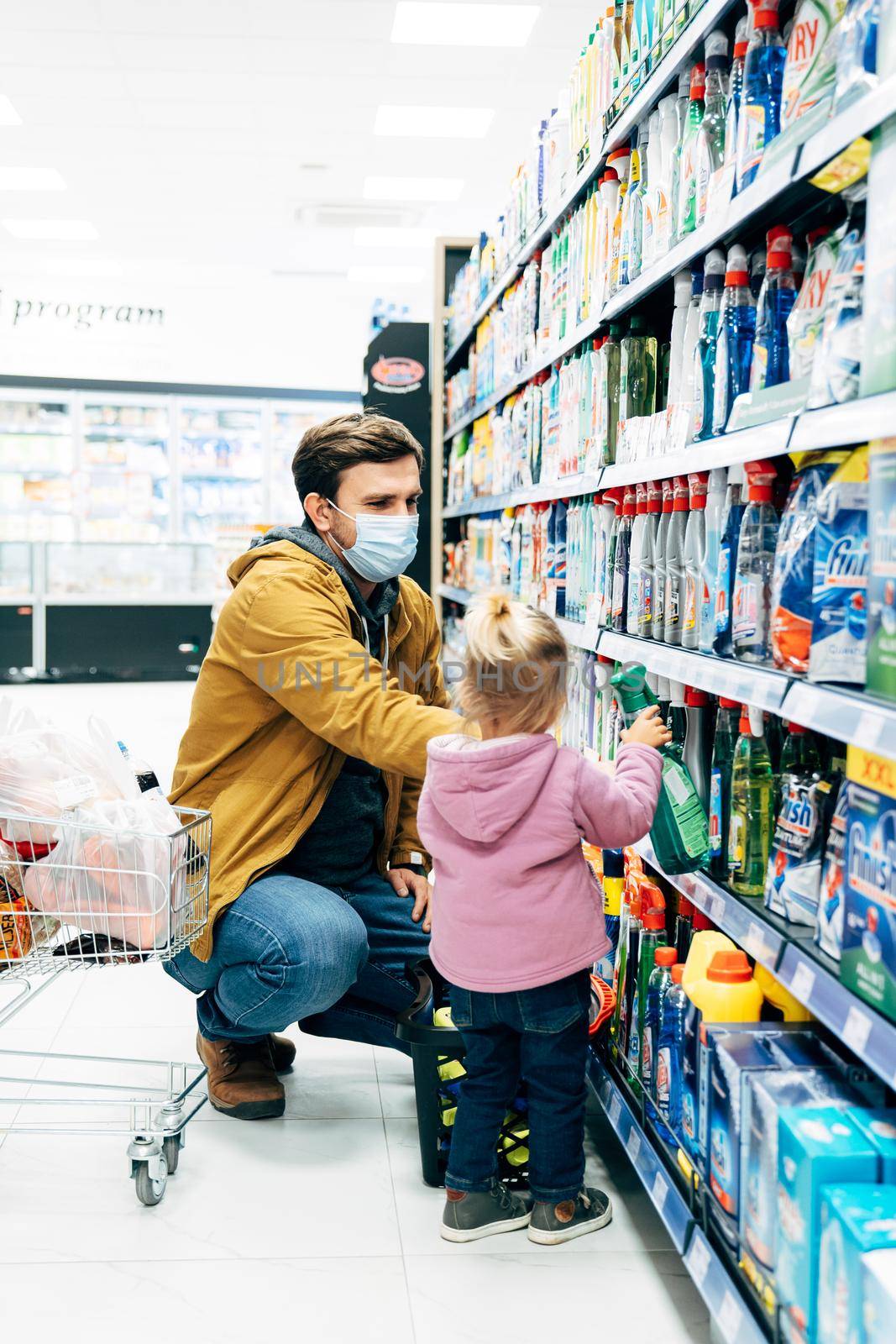 Child with a small trolley in the supermarket, shopping in the store with dad. Family at the supermarket. High quality photo