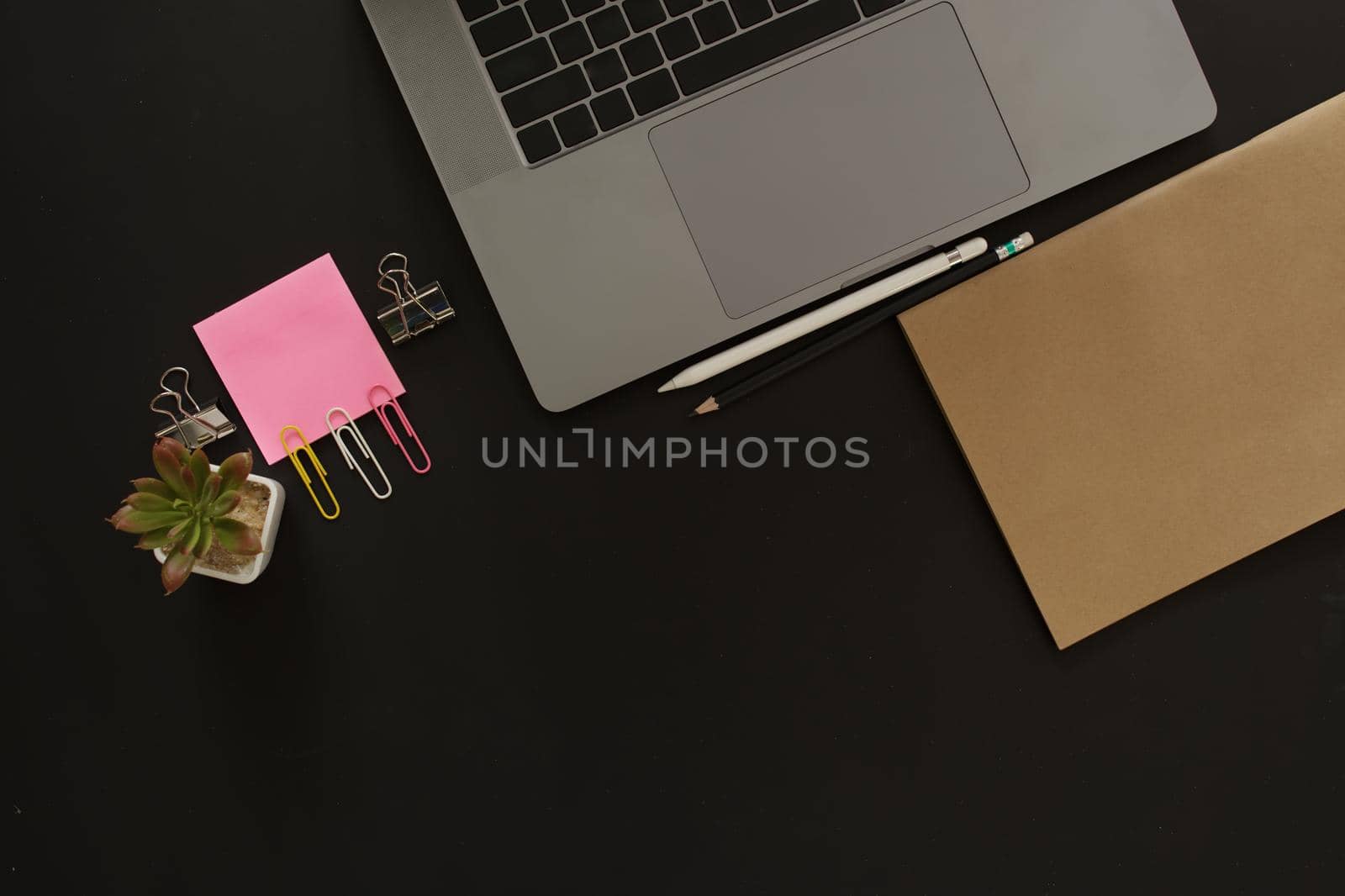 Business desk with laptop and memo paper placed on a black background, including a copy area to add text or graphics.