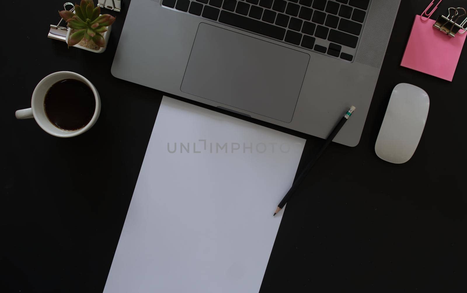 Business desk with laptop and memo paper placed on a black background, including a copy area to add text or graphics.