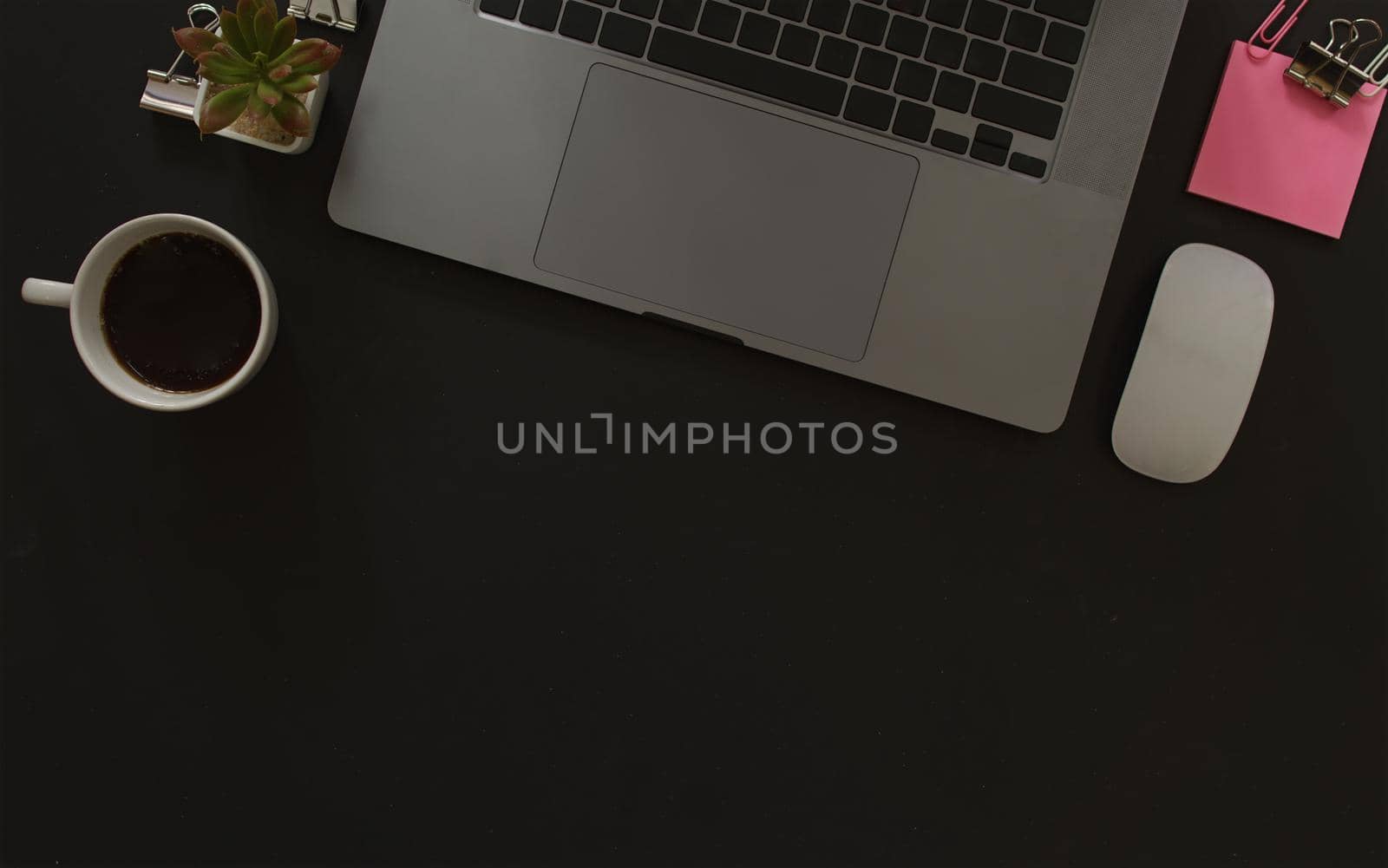 Business desk with laptop and memo paper placed on a black background, including a copy area to add text or graphics.