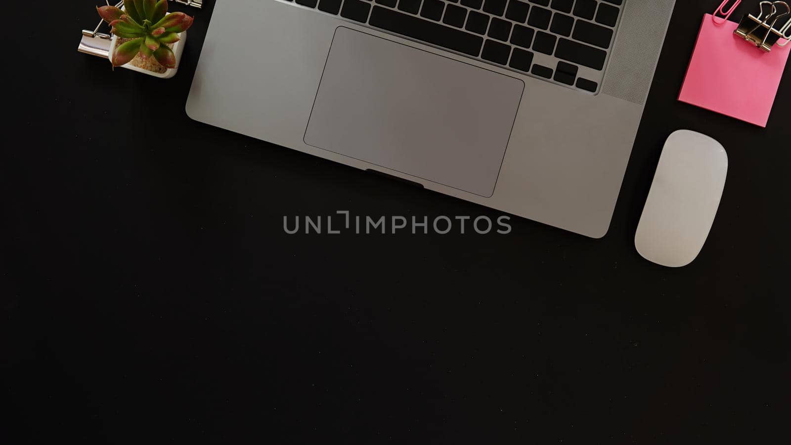 Business desk with laptop and memo paper placed on a black background, including a copy area to add text or graphics.