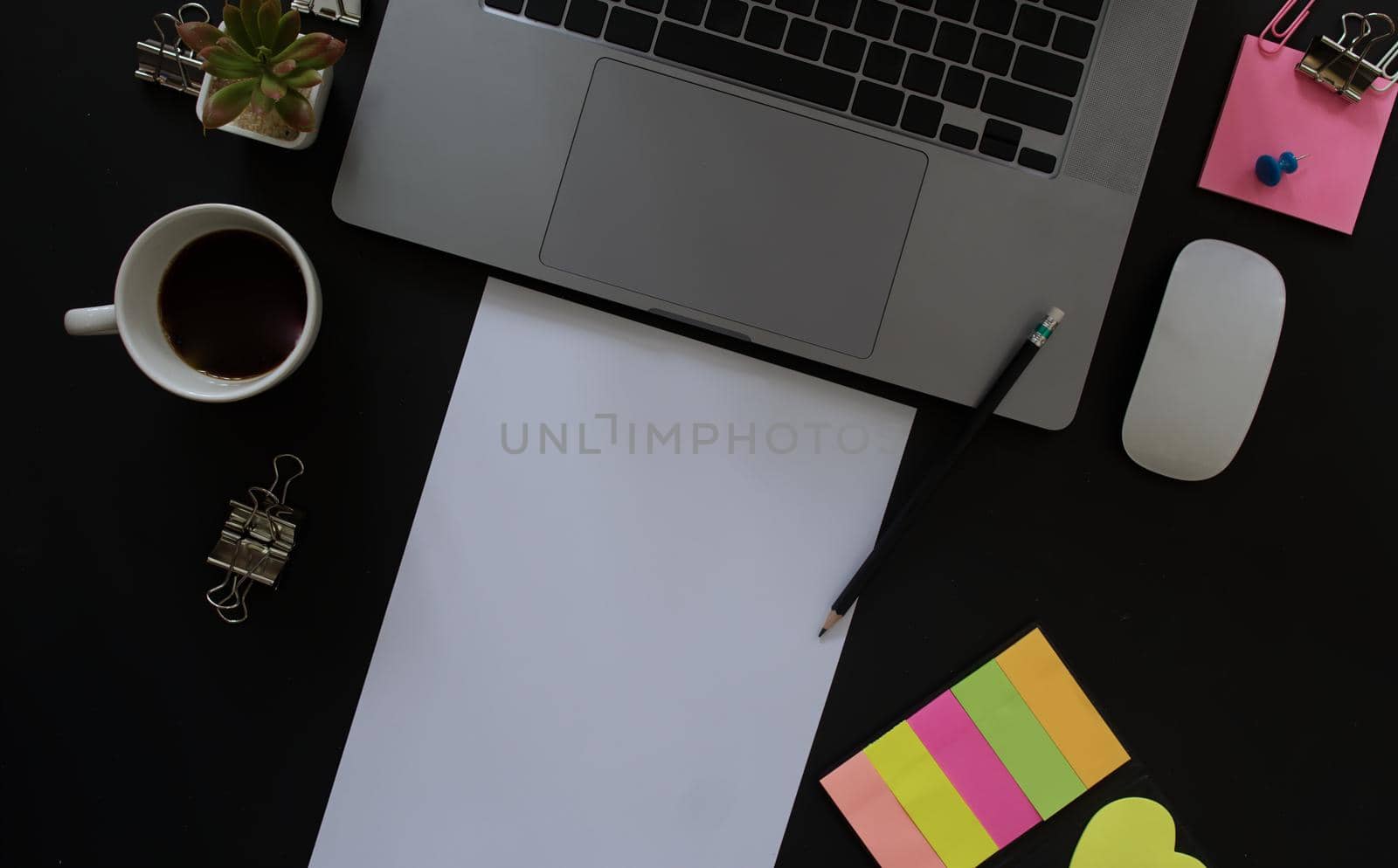 Business desk with laptop and memo paper placed on a black background, including a copy area to add text or graphics.