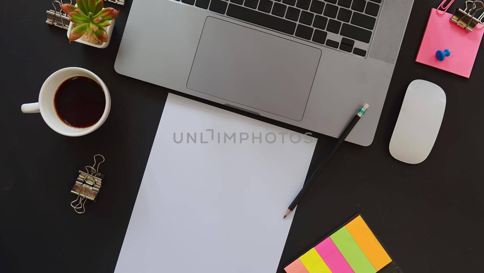 Business desk with laptop and memo paper placed on a black background, including a copy area to add text or graphics.