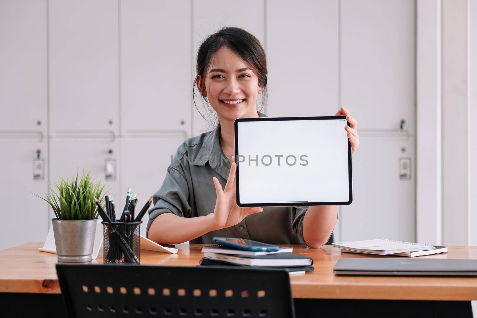 Smiling beautiful young brunette businesswoman showing blank screen tablet with copyspace area for slogan or text message