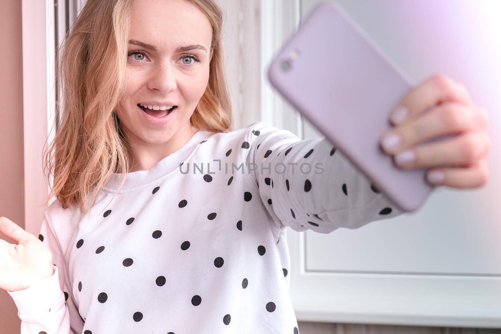 Blonde young girl taking selfie. Video call. Online education. Work from home. Woman holding smartphone. Phone call. Recording new vlog for her channel. Blogger Conference