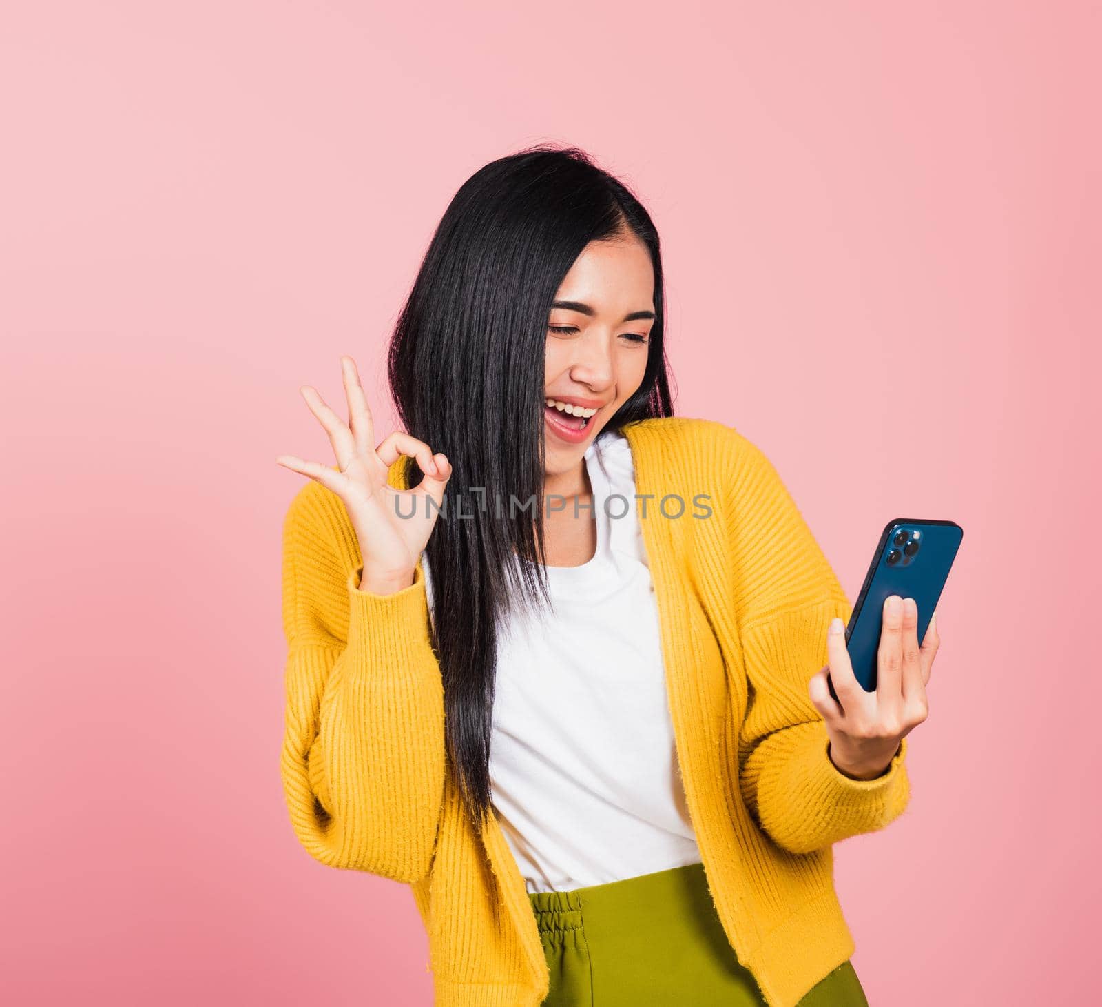 woman excited holding mobile phone and gesturing ok sign by Sorapop