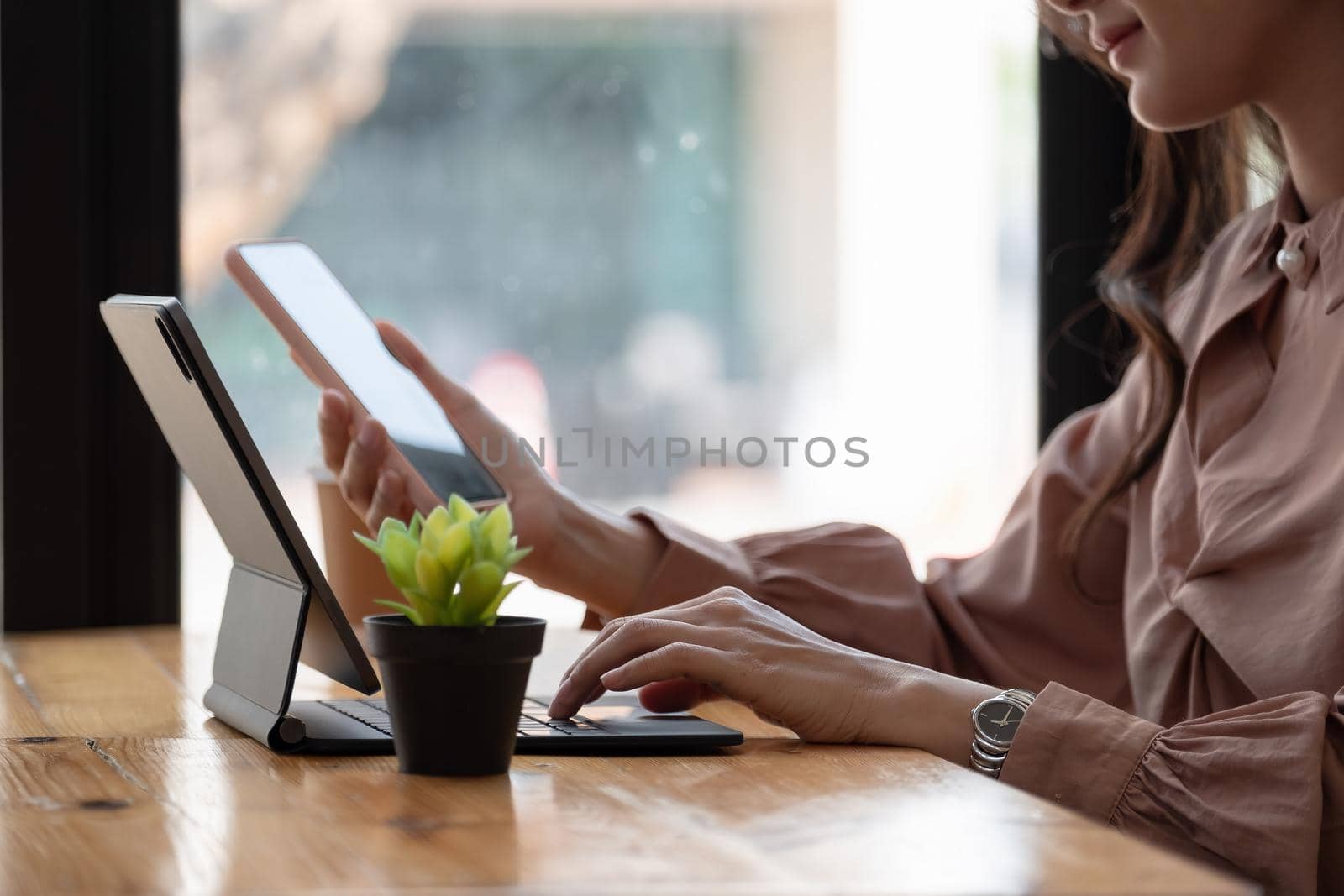 Shot of business woman holding smartphone getting message during making transaction on laptop computer.