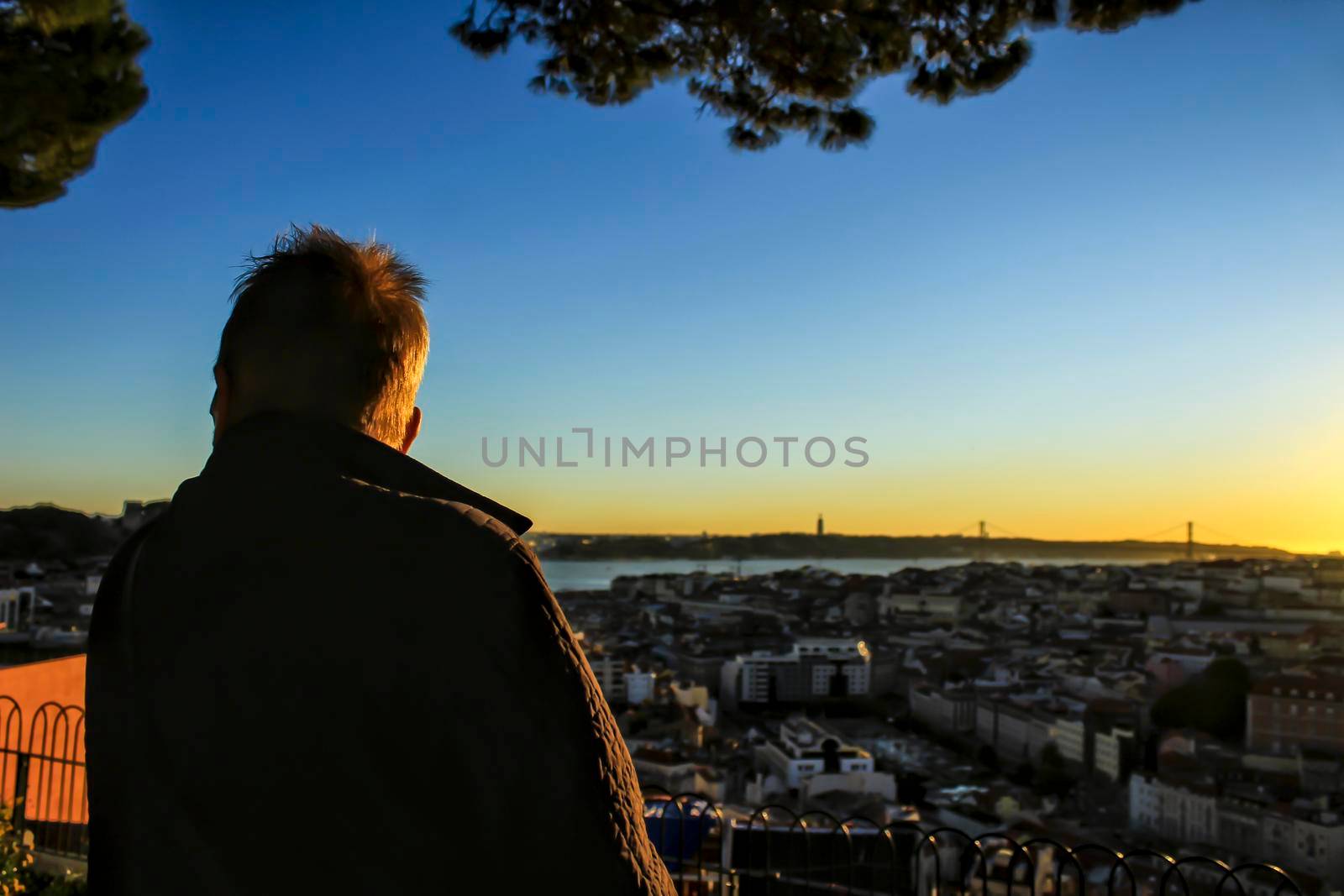 Woman watching the sunset in a viewpoint of Lisbon in Autumn