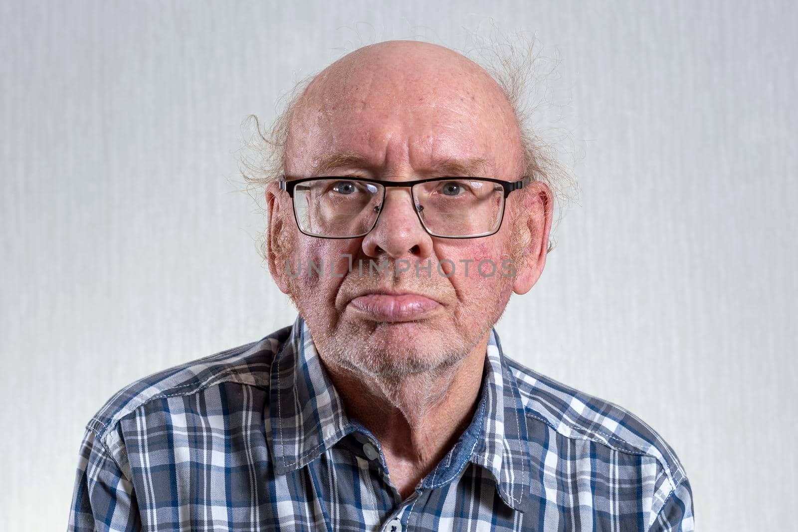 Old unshaven bald man with glasses. Indoors in daylight. Front view. by Essffes