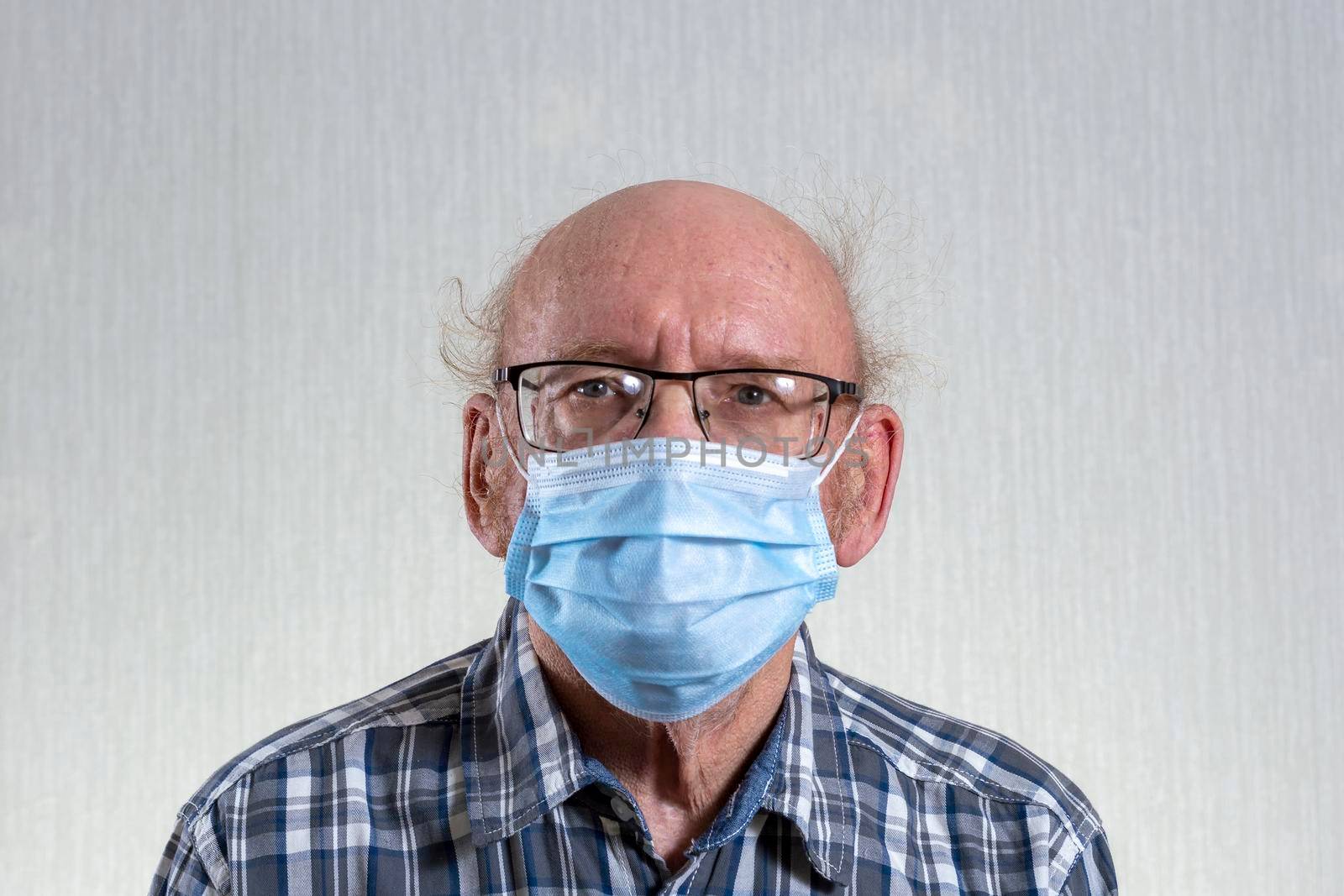 Old bald man with glasses in mask. Indoors in daylight. Front view. by Essffes