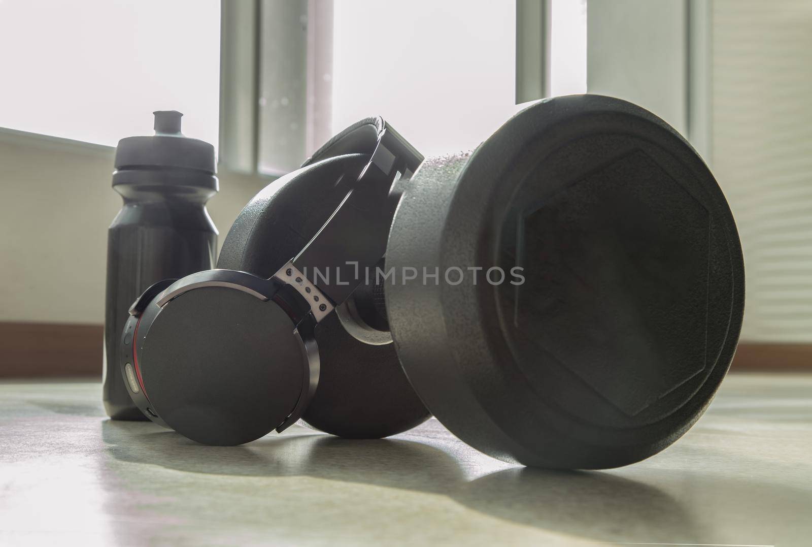 Headphones, Dumbbell and Water bottle for Listening to music while exercising. Copy space, Selective focus.
