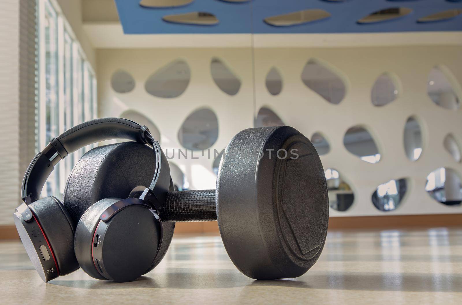 Headphones and Dumbbell  for Listening to music while exercising at Fitness studio. Copy space, Selective focus.