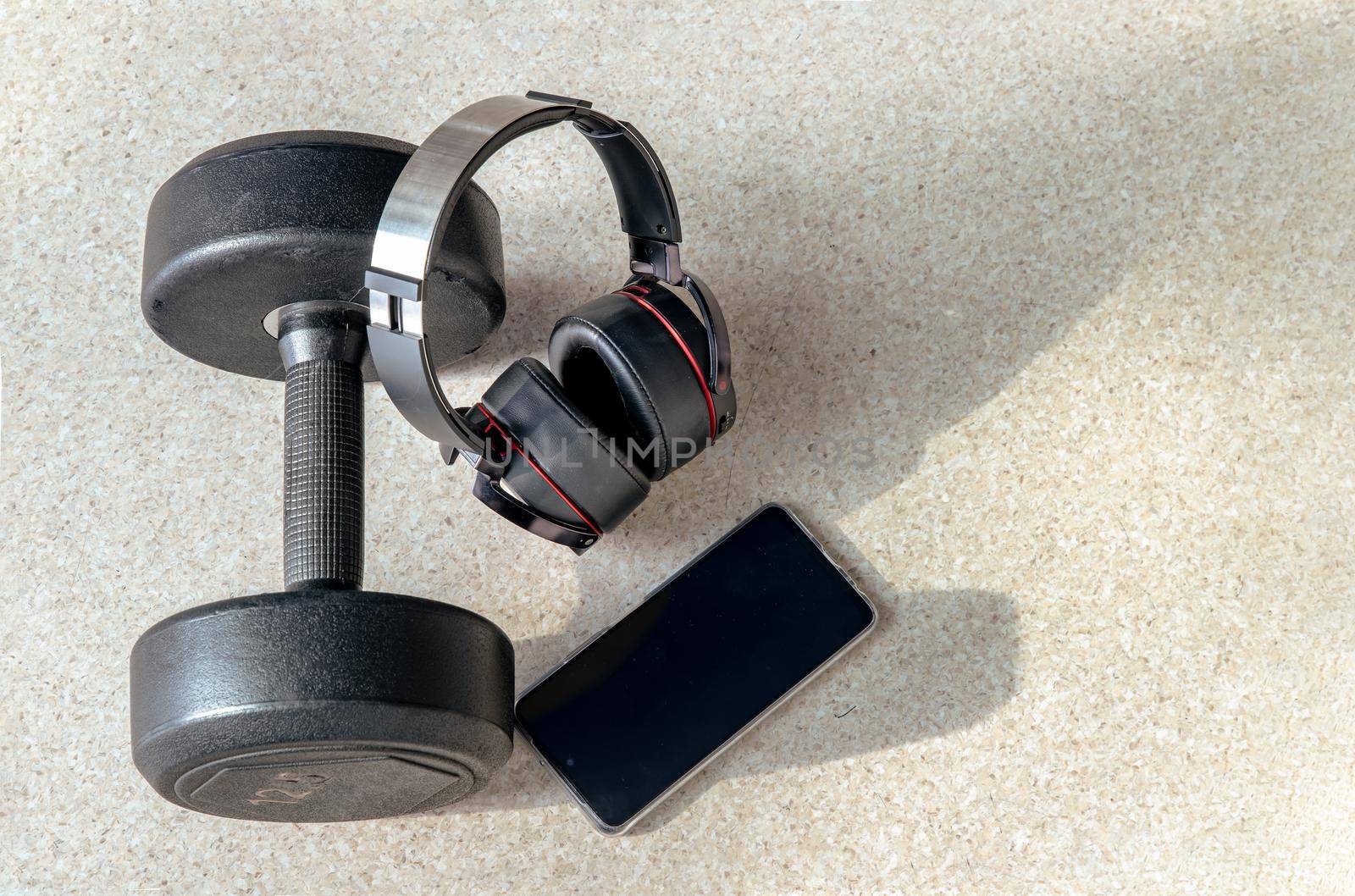 Composition of Smartphone, Headphones and Dumbbell for Listening to music while exercising. Copy space, Selective focus.