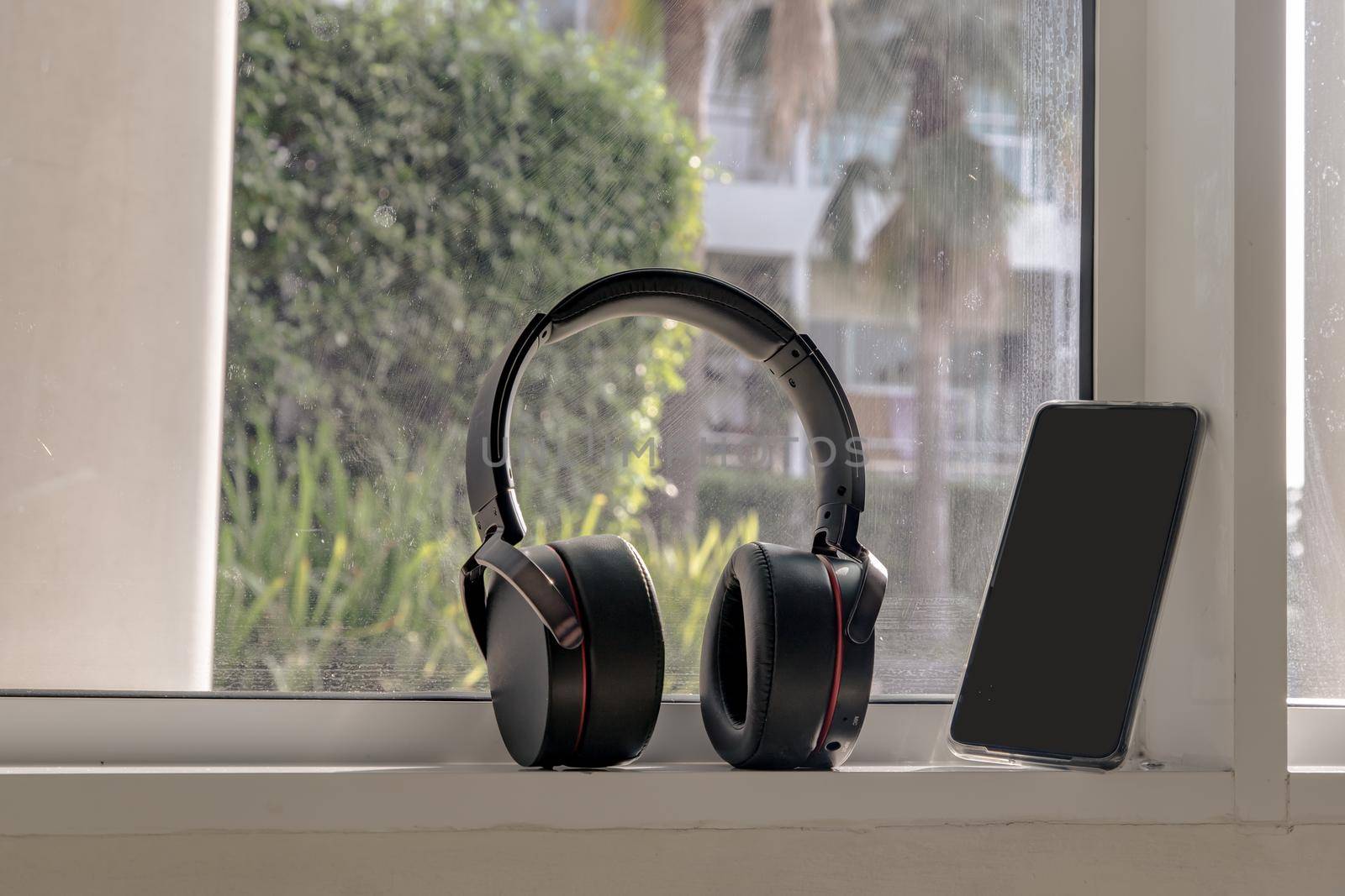 Smartphone and Headphones for listening to music Placed on glass wall In the time of rest. Personal device with Space for text. Selective focus.