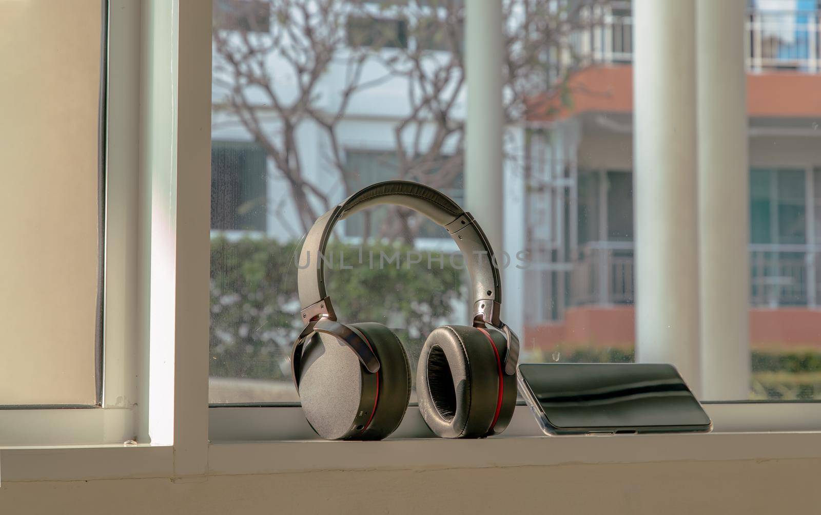 Smartphone and Headphones for listening to music Placed on glass wall In the time of rest. Personal device with Space for text. Selective focus.