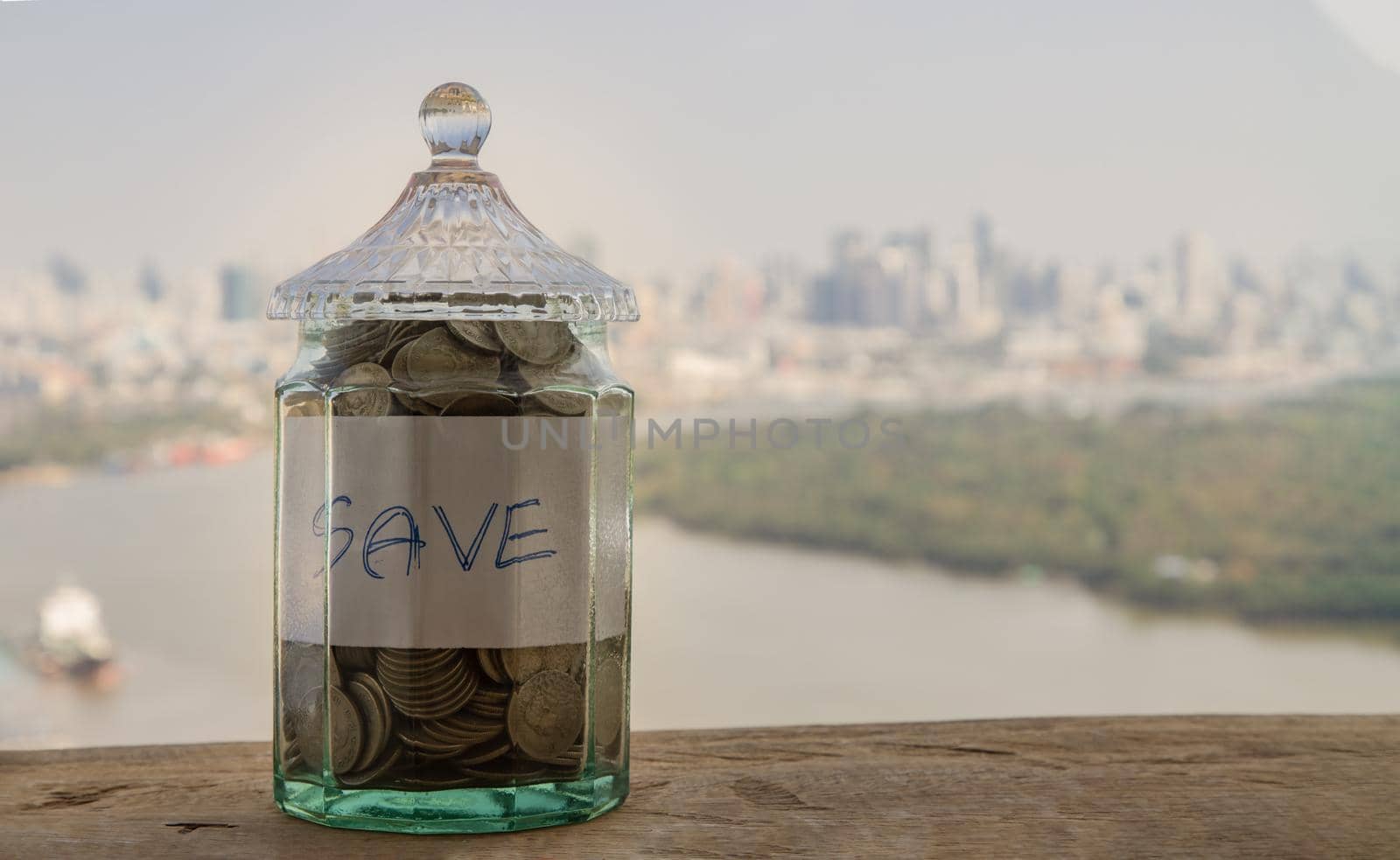 The pile of coins in glass bottle on cityscape background for concept for growth and saving money. Space for text input, Selective focus.
