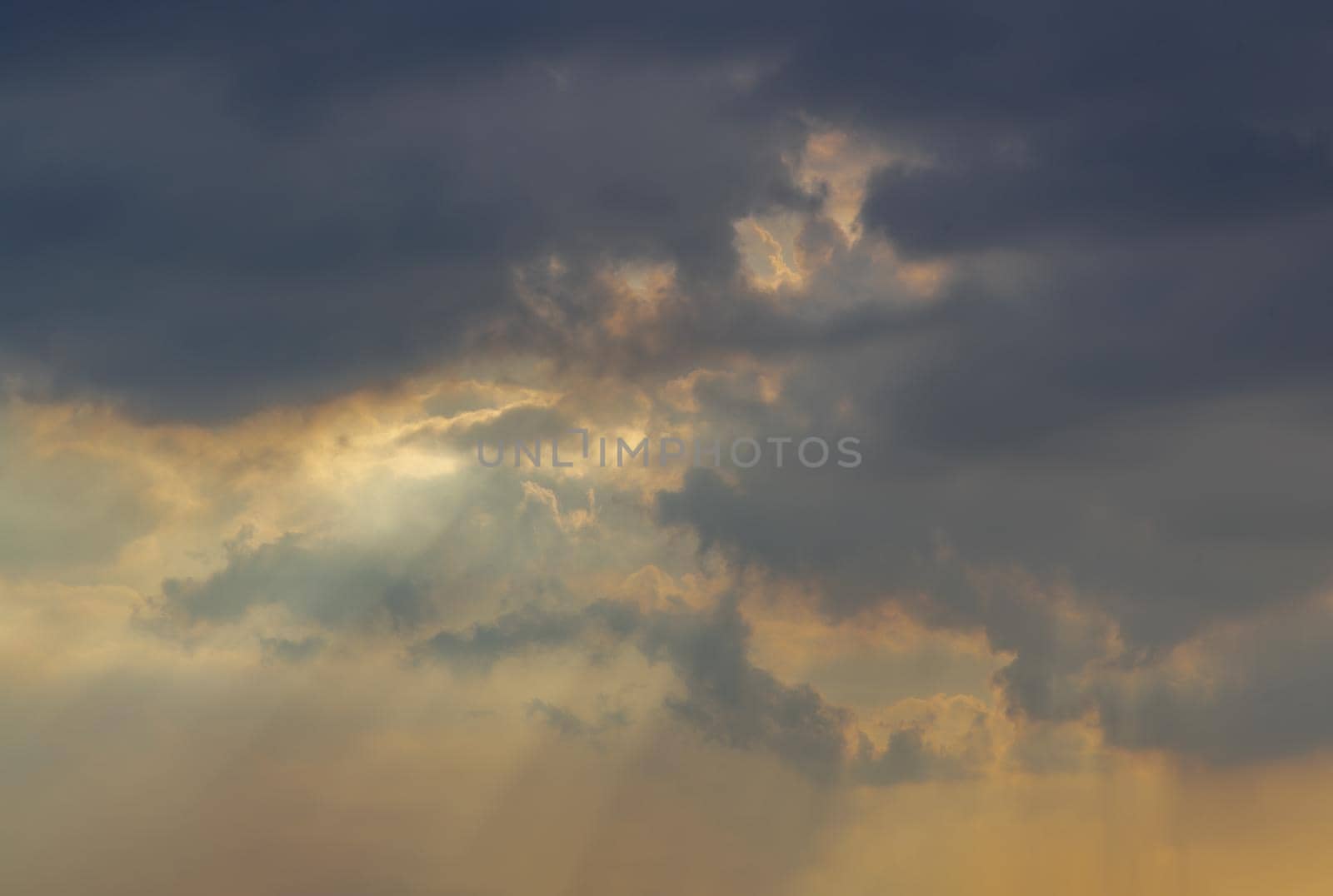 The sun's rays passing through the clouds and shining form an interesting light pattern against the sky evening. Copy space, No focus, specifically.