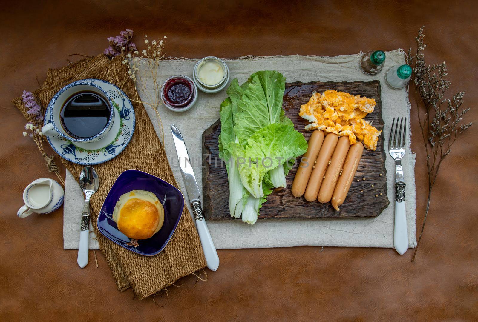 Continental breakfast with scrambled eggs, fried sausages, vegetable and scones served with coffee with milk. Wood background, Selective focuse.