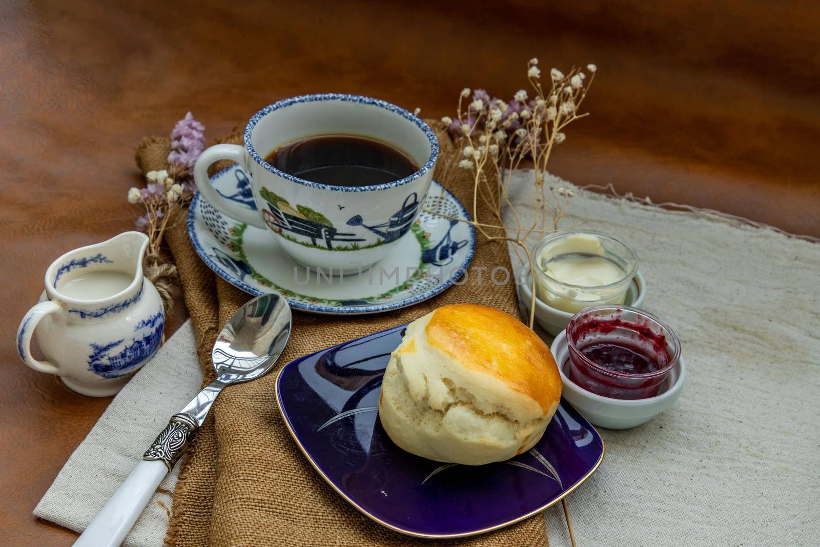 Scones with mascarpone cheese and raspberry jam served with black coffee with milk on sack cloth for new morning. Selective focuse.