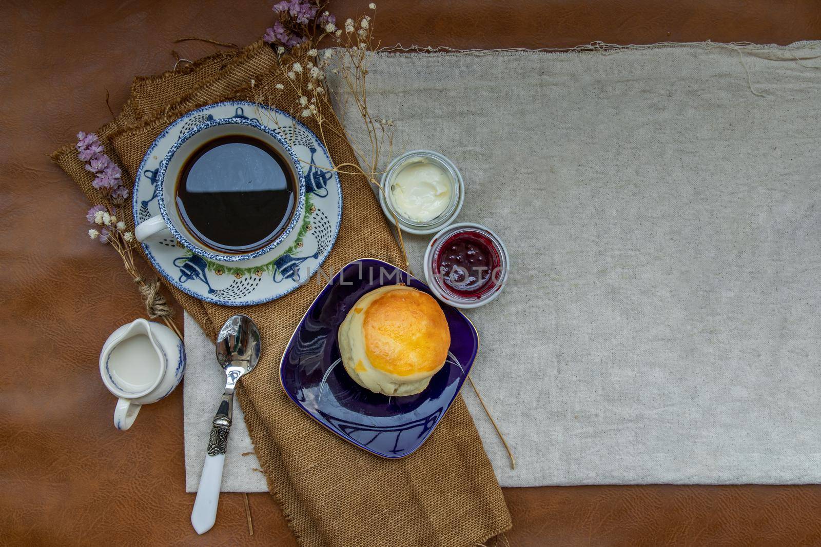 Scones with mascarpone cheese and raspberry jam served with black coffee with milk on sack cloth for new morning. Selective focuse.