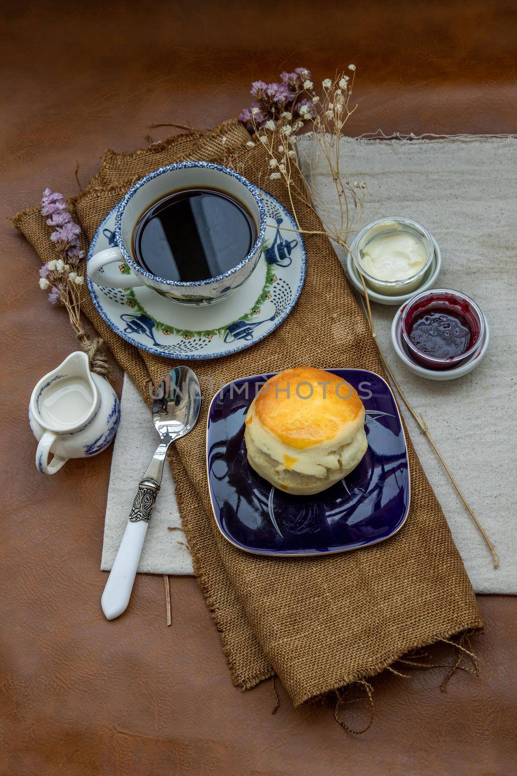Scones with mascarpone cheese and raspberry jam served with black coffee with milk on sack cloth for new morning. Selective focuse.