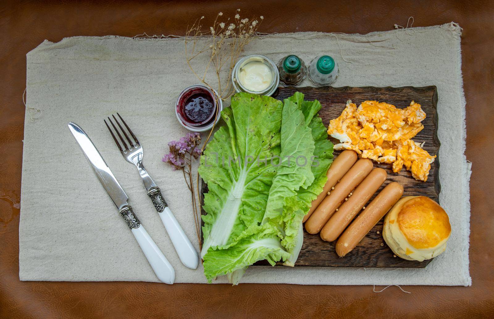 Continental breakfast with scrambled eggs, fried sausages, vegetable and scones served with cmascarpone cheese and raspberry jam on  Wooden background, Selective focuse.