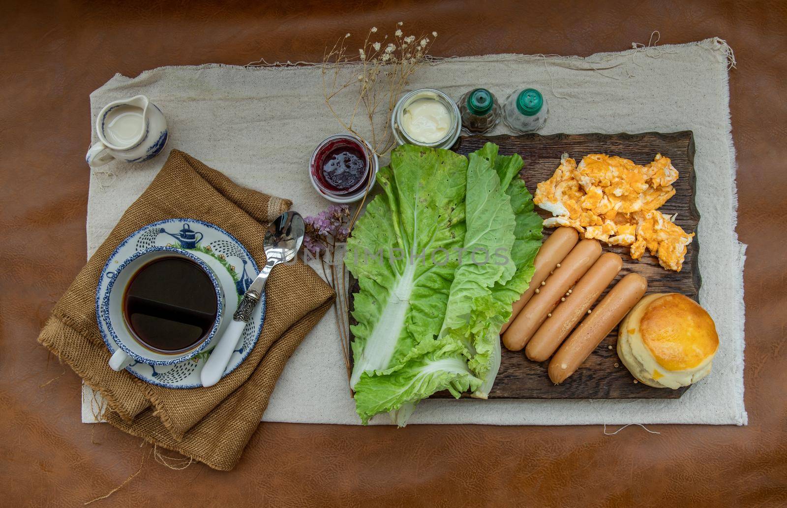 Continental breakfast with scrambled eggs, fried sausages, vegetable and scones served with coffee with milk. Wood background, Selective focuse.
