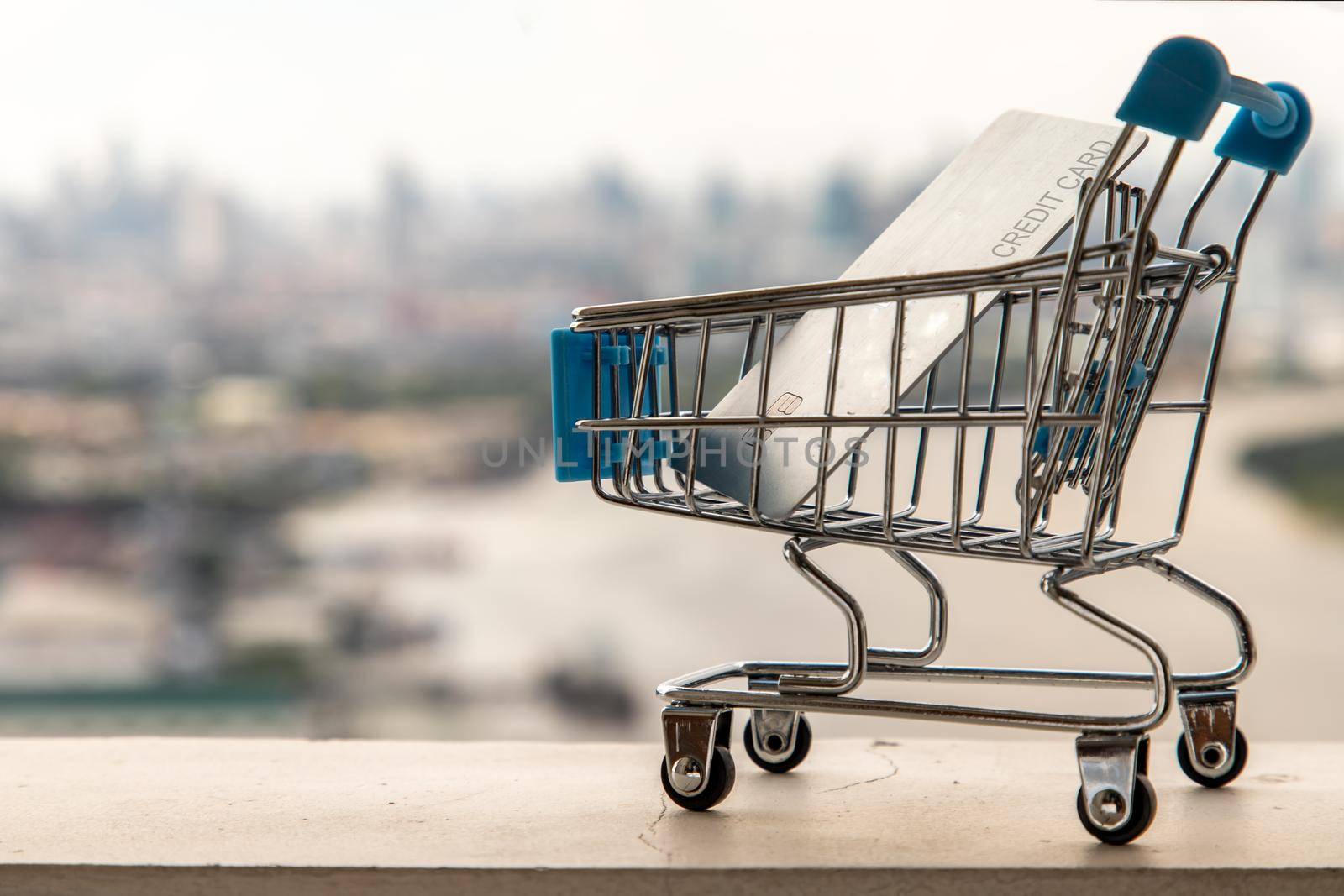 A credit card in a Mini supermarket trolley on Cityscape background. Ideas about home online shopping.