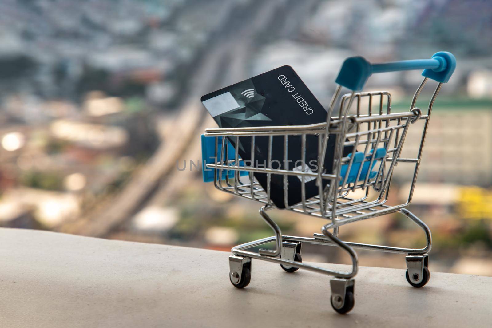 A credit card in a Mini supermarket trolley on Cityscape background. Ideas about home online shopping.