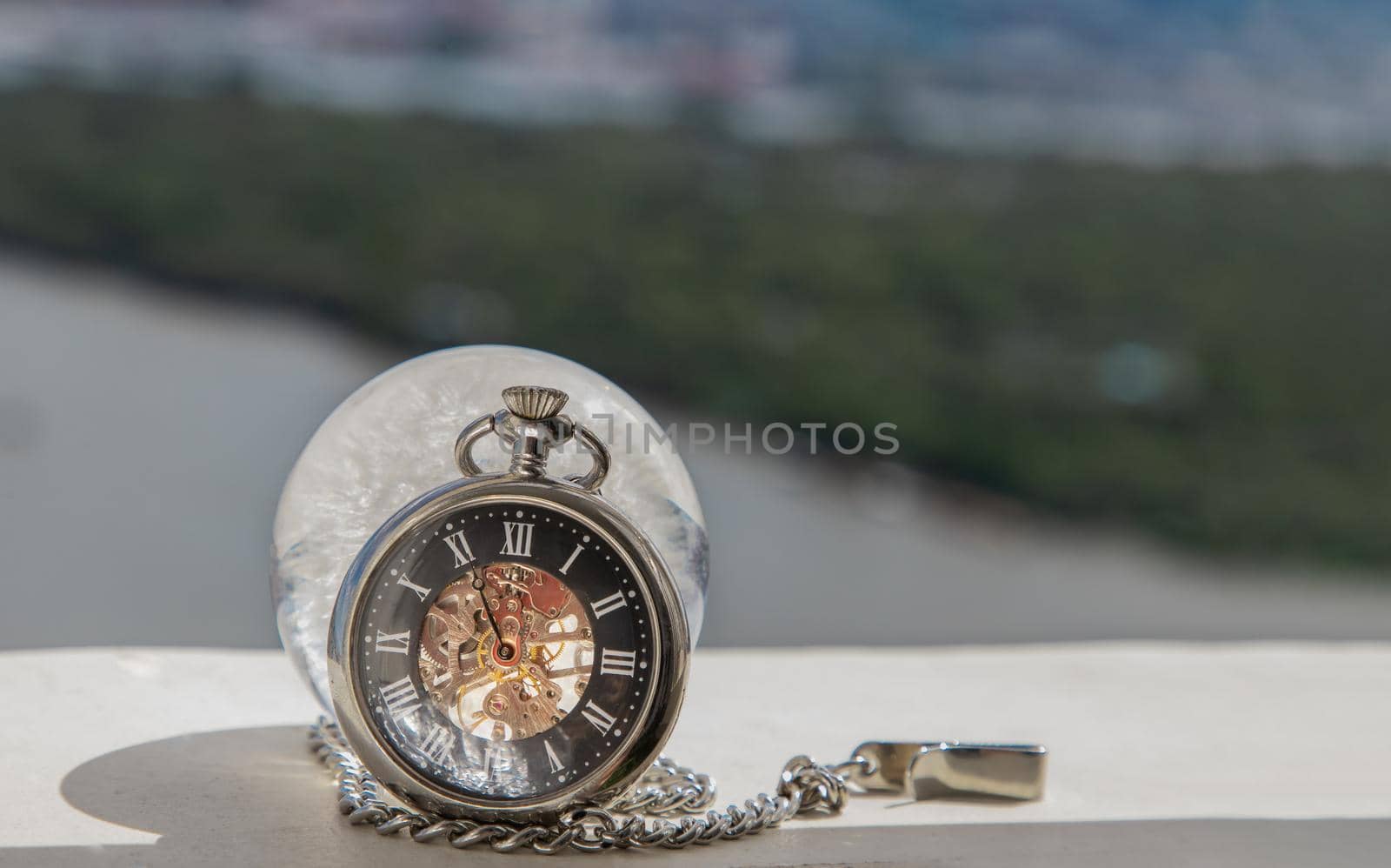 A retro pocket watch In front of Crystal glass in river background. World Environment concept, nature background. Copy space.