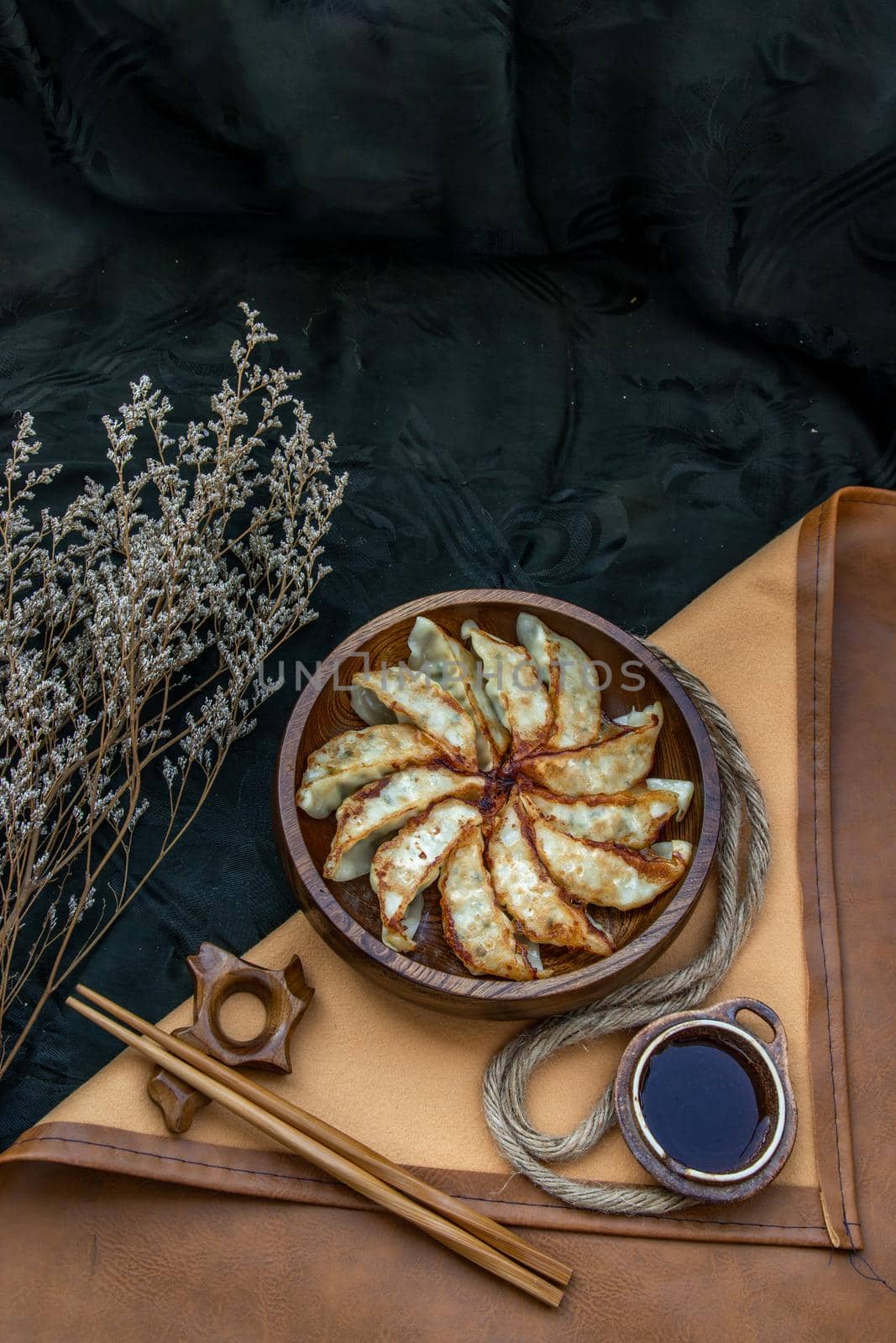Fried japanese gyoza dumplings on wooden bowl served with soy sauce and chopsticks. Asian dinner, Top view, Selective focus.