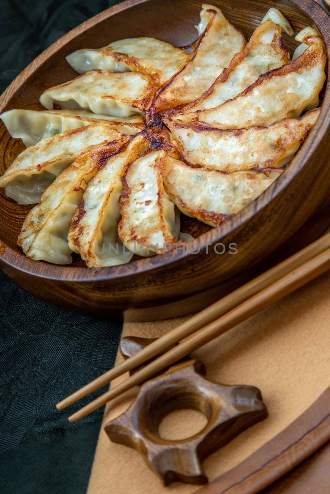 Fried japanese gyoza dumplings on wooden bowl served with soy sauce and chopsticks. Asian dinner, Selective focus.