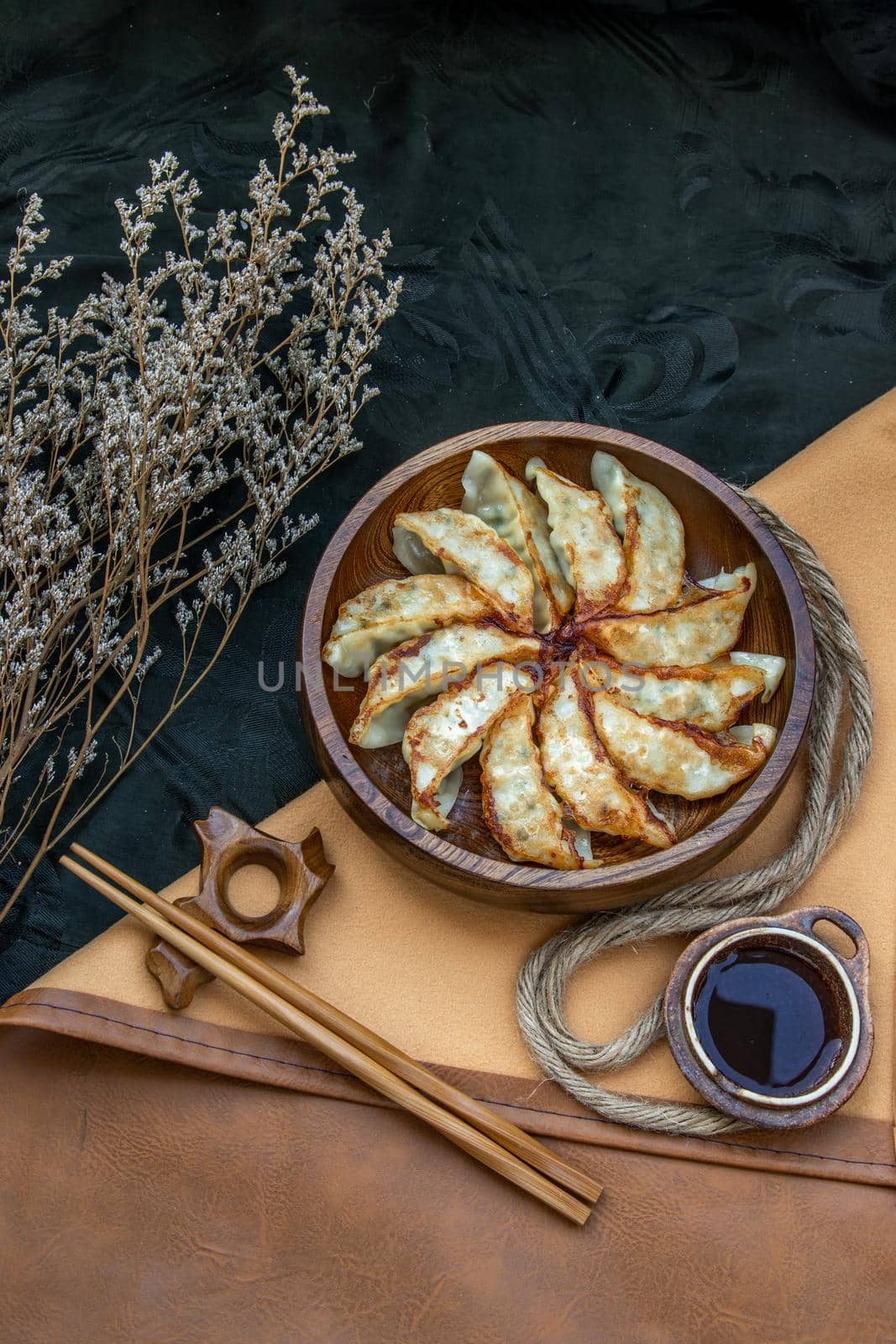 Fried japanese gyoza dumplings on wooden bowl served with soy sauce and chopsticks. Asian dinner, Top view, Selective focus.