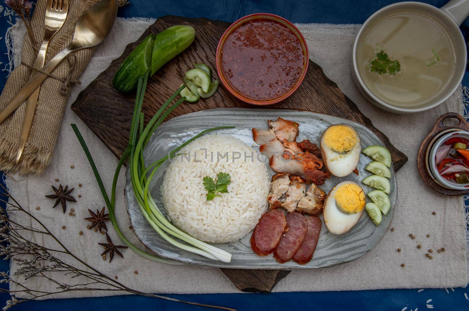 Red pork with rice (Kao Moo Dang) : Thai Style Red Barbecue Pork, duck egg and crispy pork belly, sliced cucumber with red sauce and broth. Horizontal top view