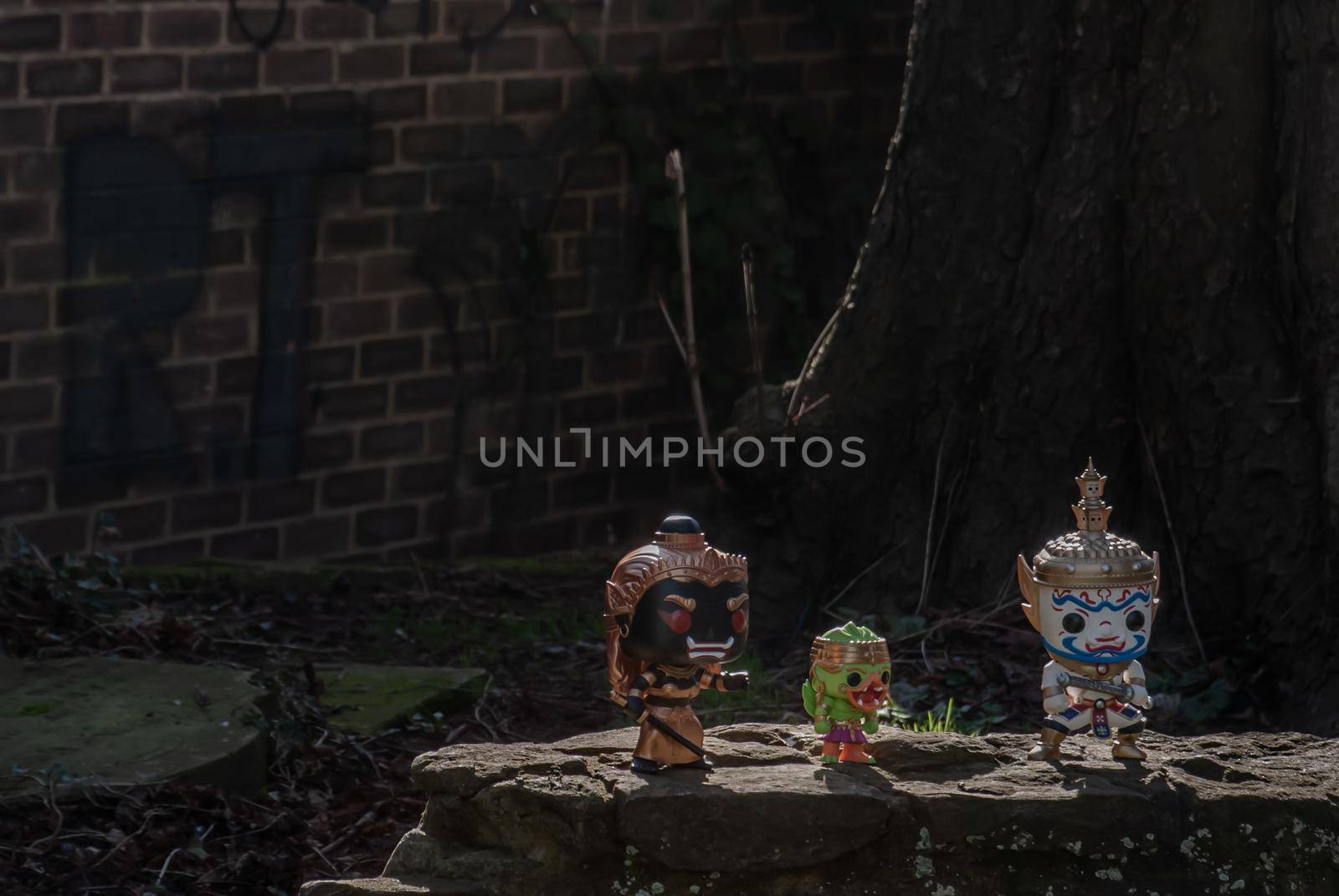 Ravana, Giantess and Hanuman Standing on a stone fence around a large tree In the cemetery. Traveller doll.