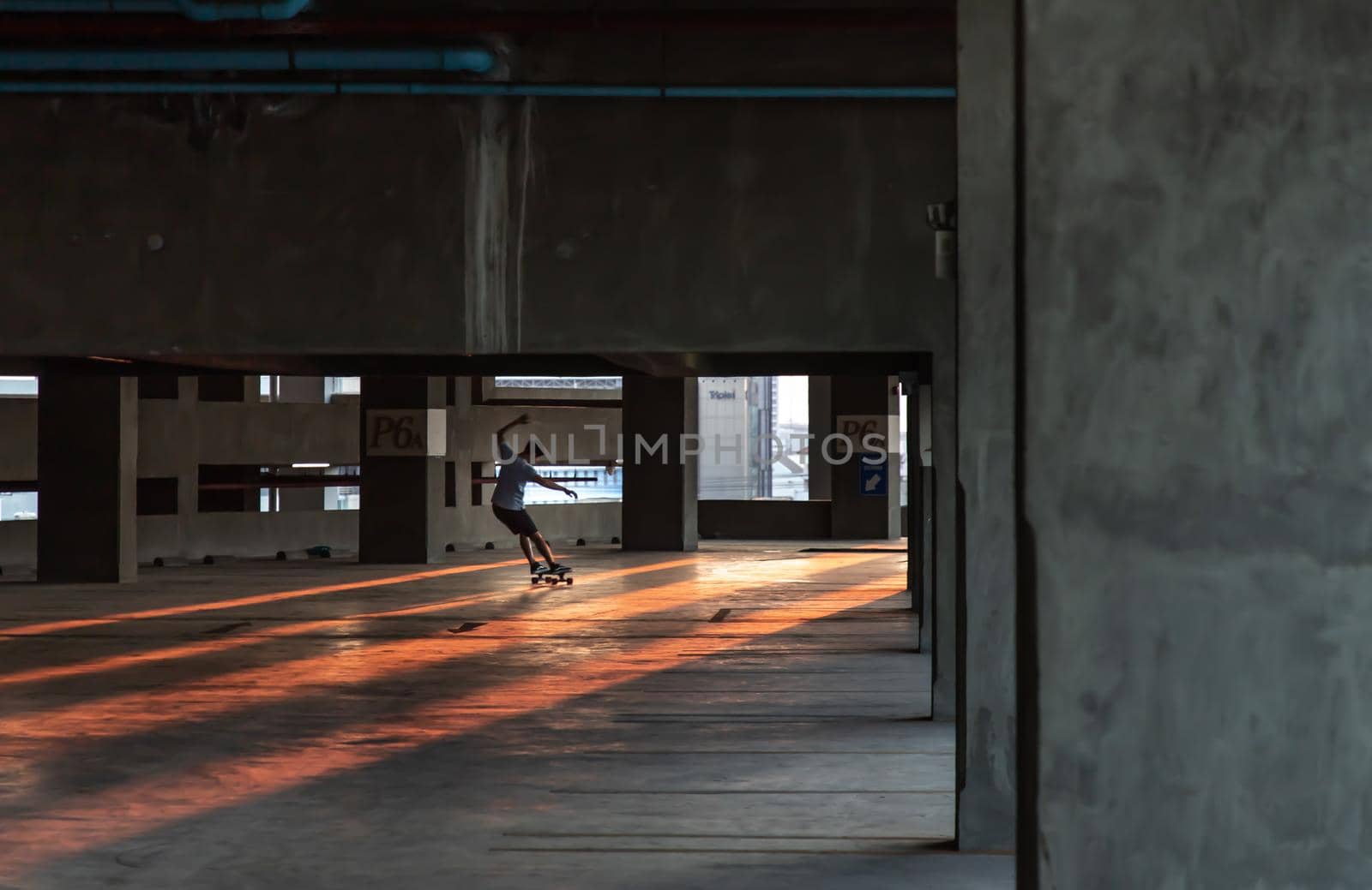 Bangkok, thailand - Mar 26, 2020 : A young man riding a skateboard in a parking lot at evening. The concept of modernity, youth and active lifestyle. No focus, specifically.