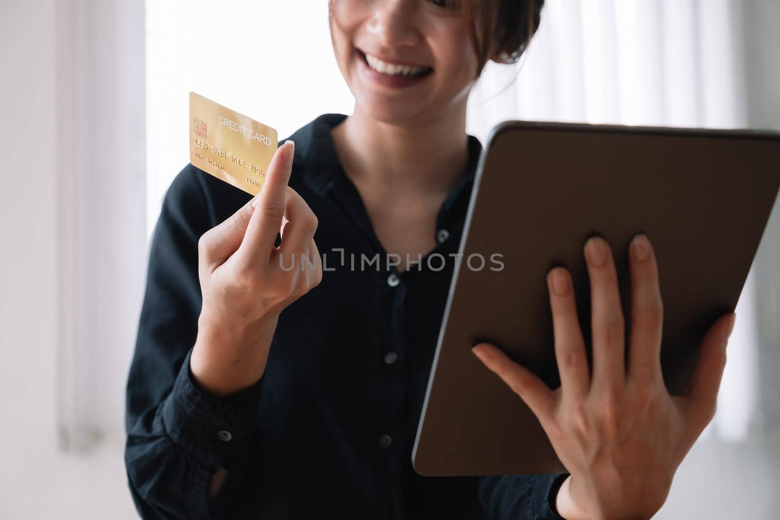 Asian woman making online payment using laptop and credit card for shopping at home. by nateemee