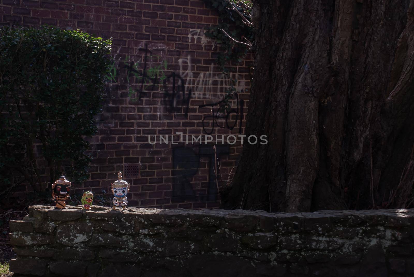 Ravana, Giantess and Hanuman Standing on a stone fence around a large tree In the cemetery. Traveller doll.