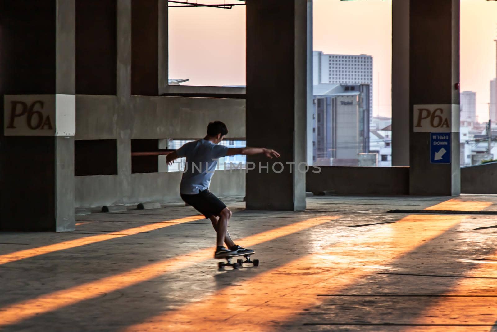 Bangkok, thailand - Mar 26, 2020 : A young man riding a skateboard in a parking lot at evening. The concept of modernity, youth and active lifestyle. No focus, specifically.