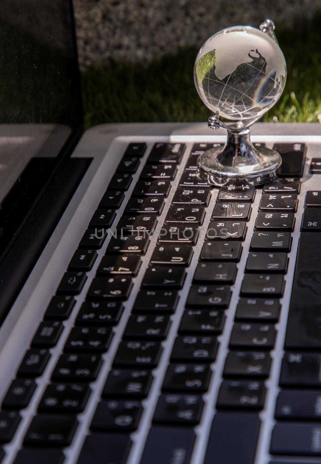 Glass crystal globe on Laptop keyboard. Concept for global communication and business. Selective focus.