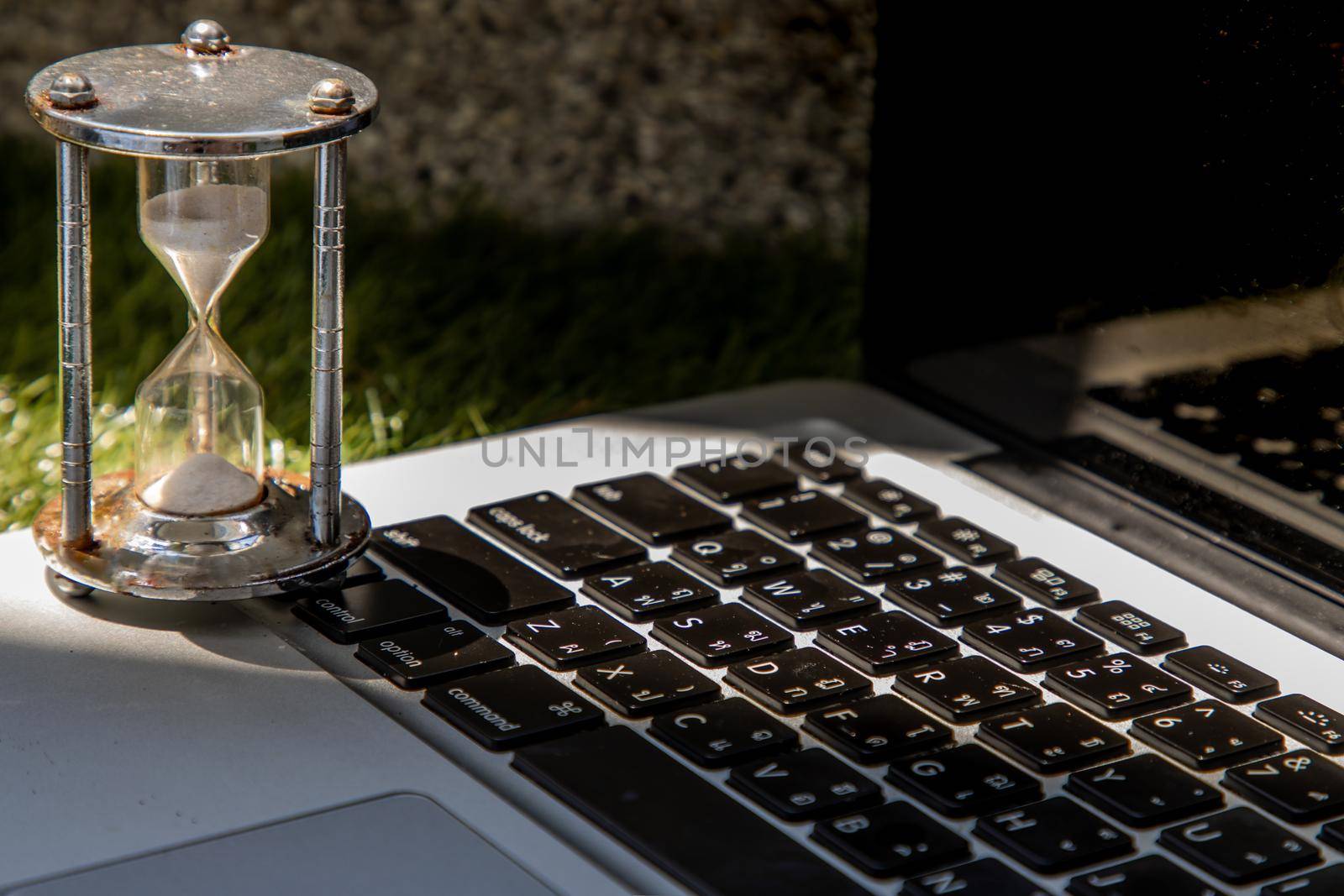 Hourglass on laptop keyboard. Time management concept and Countdown to deadline. Selective focus.