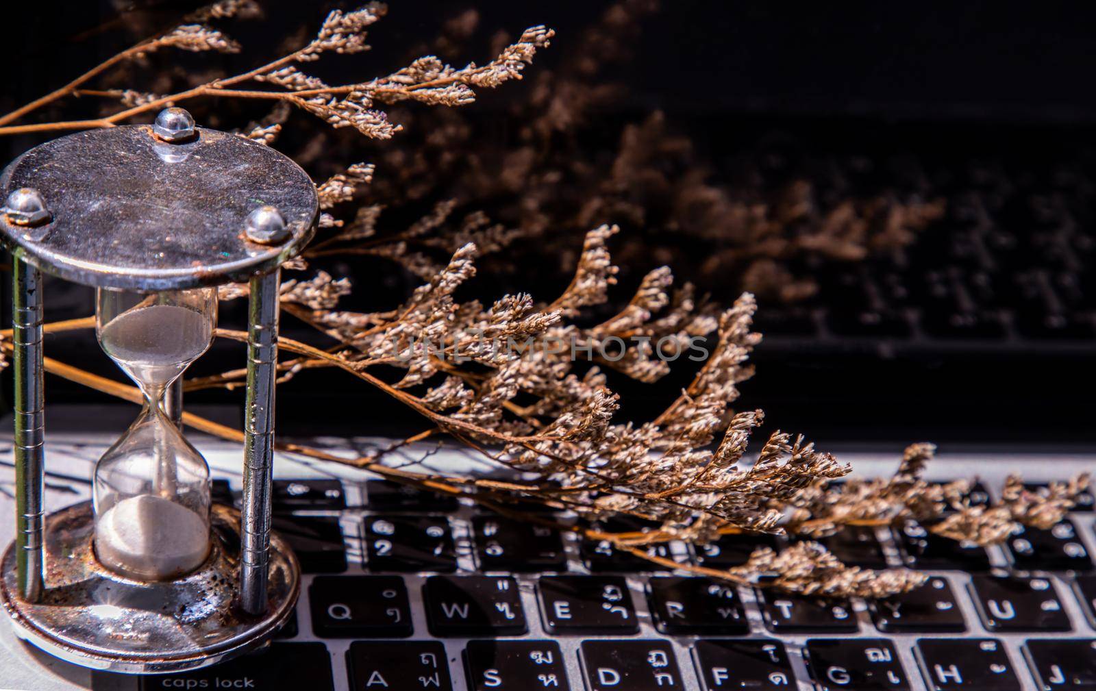 Hourglass on laptop keyboard. Time management concept and Countdown to deadline. Selective focus.