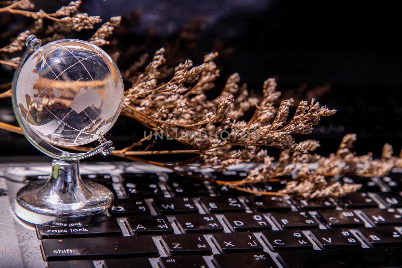 Glass crystal globe on Laptop keyboard. Concept for global communication and business. Selective focus.